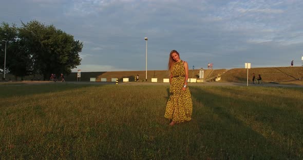 Beautiful women walking barefoot in grass at sunset