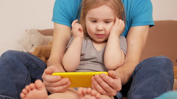 Father and Daughter Watch Cartoon on Phone Home Interior Training