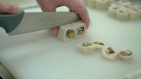 Close Up Cutting Japanese Rolls with Fried Fish and Fresh Vegetables