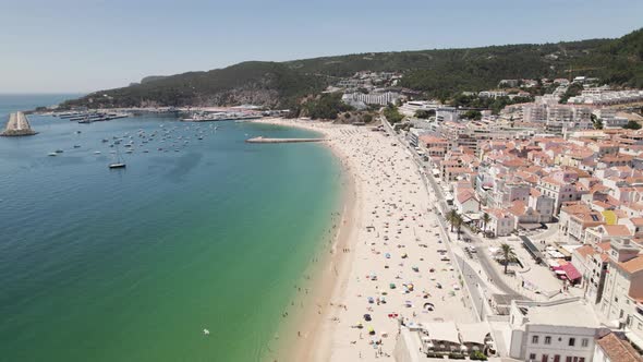Aerial backwards view of long and beautiful beach with its bay in Sesimbra. Portugal. Real time