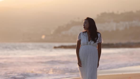 Pregnant Asian woman enjoying walk on the beach