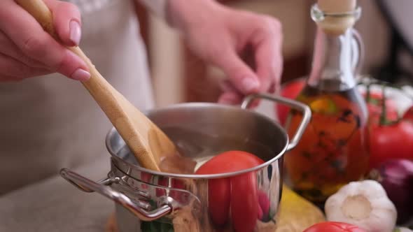 Woman Blanching Tomato in Pot with Hot Boiling Water