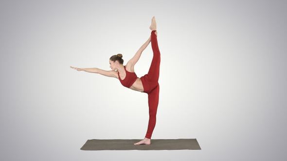 Slim woman standing in yoga pose dandayamana dhanurasana