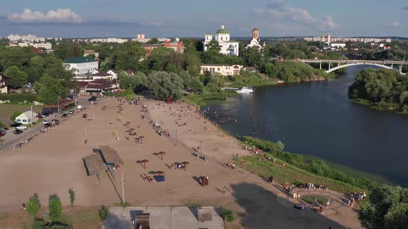 Summer flight over the beach and the river. In the background are churches and a bridge.