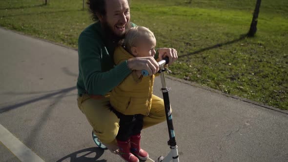 Father and son riding on scooter in public playground, Zagreb, Croatia.