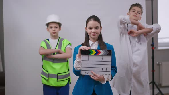 Talented Teenage Girl Clicking Clapper Board Smiling Looking at Camera As Boys in Doctor and Builder