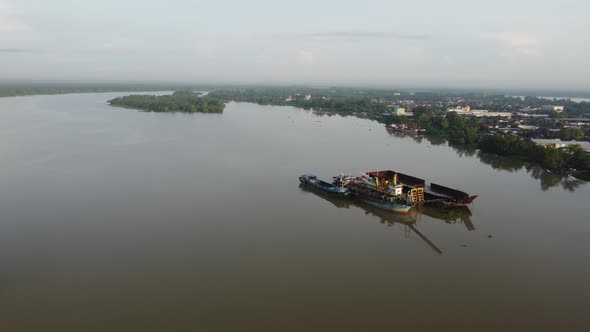 Aerial fly toward ship used for river sand mining