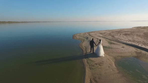 Bride and Groom Walk Along the Beach. Aerial