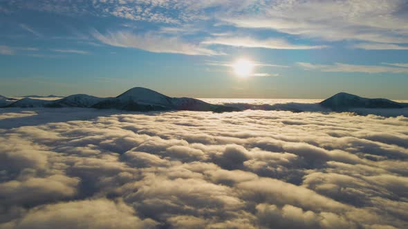 Aerial view of vibrant sunrise over white dense fog with distant dark peaks of Carpathian