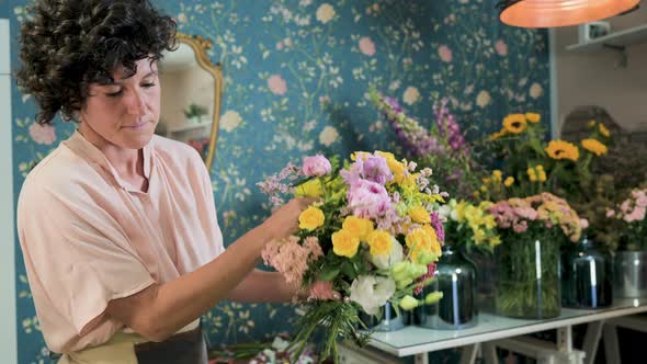 Woman arranging flowers in bouquet in floral shop