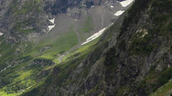 Detail pan-up shot of a green valley in the Alps unveiling the permanent snow of the glacier in ProR