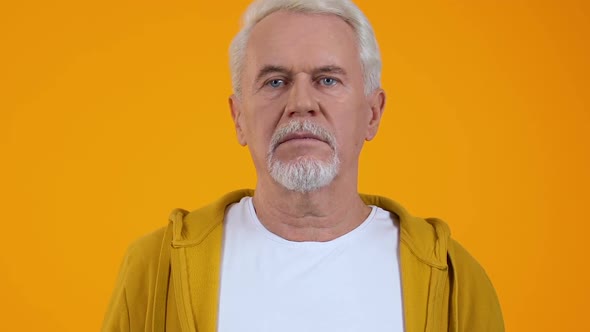 Surprised Retired Man on Orange Background, Shocking News, Unexpected Problem