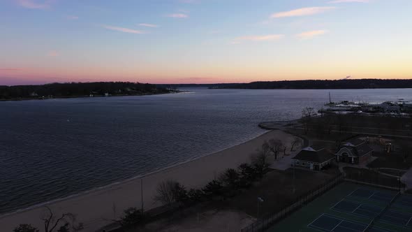 an aerial shot over an empty park during a beautiful sunrise. The sky is pink and blue with a few cl