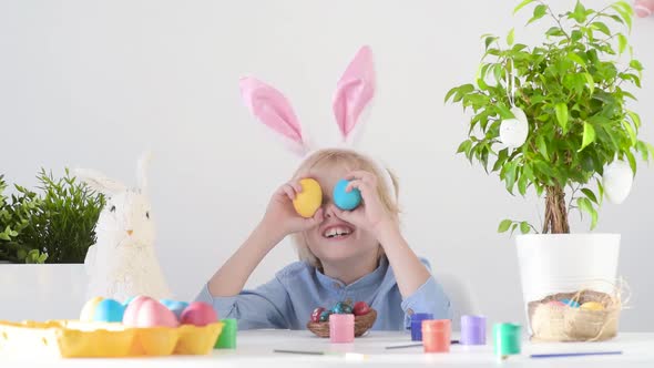 Cute boy having fun with colored eggs for Easter holiday