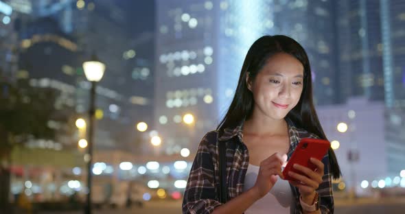 Woman use of mobile phone online in city at night