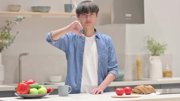 Young Asian Man Showing Thumbs Down While Standing in Kitchen