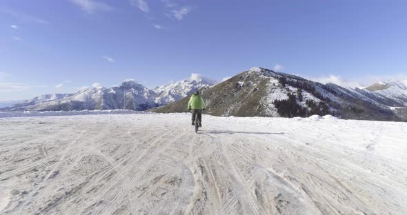 Forward Aerial Over Biker Man Cycling on Snowy Path During Winter with Mtb Ebike