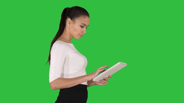 Attractive Businesswoman Using a Digital Tablet While Walking