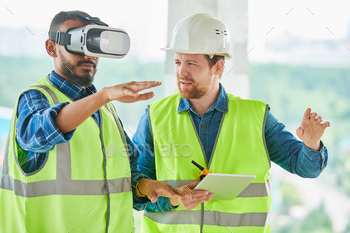 rd gesturing while using VR simulator for building visualization, his colleague explaining project to him