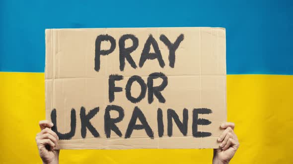 Cardboard Saying Pray for Victims in Ukraine with Yellow and Blue Flag