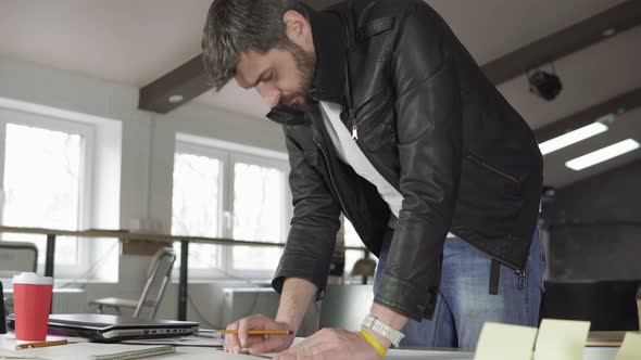 Young Man Working on a Project Drawing and Thinking in Modern Office