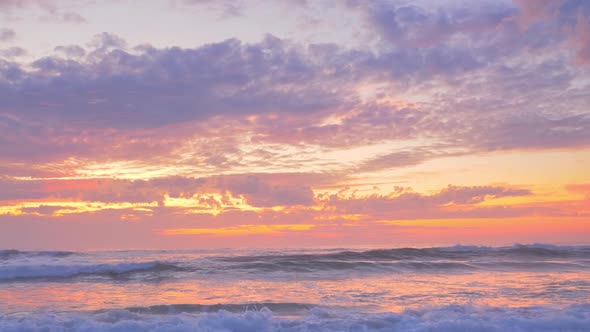 Clouds, golden sand, foaming waves of ocean at summer sunset