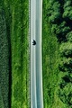 Aerial top view of a asphalt road with a car through green forest and corn field - PhotoDune Item for Sale