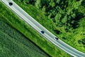 Aerial top view of a asphalt road with a car through green forest and corn field - PhotoDune Item for Sale