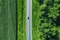 Aerial top view of a asphalt road with a car through green forest and corn field - PhotoDune Item for Sale