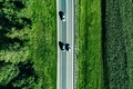 Aerial top view of a asphalt road with a car through green forest and corn field - PhotoDune Item for Sale