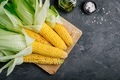 Fresh sweet golden corn on cobs on dark gray stone background - PhotoDune Item for Sale