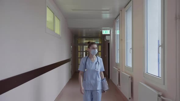 A Masked Doctor Walks Down the Corridor of the Hospital