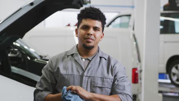 African American male car mechanic cleaning his hands with a rag and looking at the camera