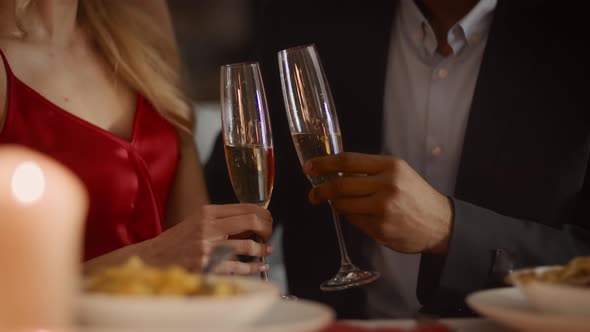 Unrecognizable Diverse Couple Clinking Glasses Drinking Sparkling Wine In Restaurant