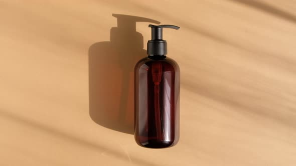 Brown Glass Bottle on Pastel Beige Background in the Morning Rays of Light