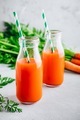 Fresh detox carrot juice in glass bottles on a gray stone background - PhotoDune Item for Sale