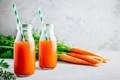 Fresh detox carrot juice in glass bottles on a gray stone background - PhotoDune Item for Sale