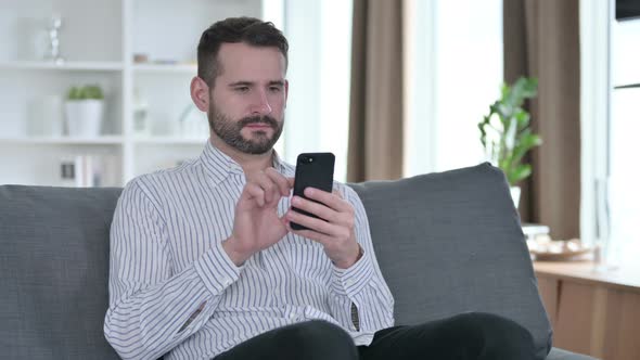 Serious Young Businessman Using Smartphone at Home 