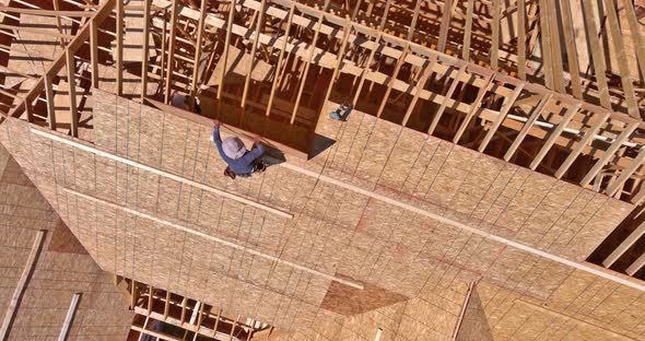 Carpenter Applying Plywood to Roof of Addition on Home Roofing Construction