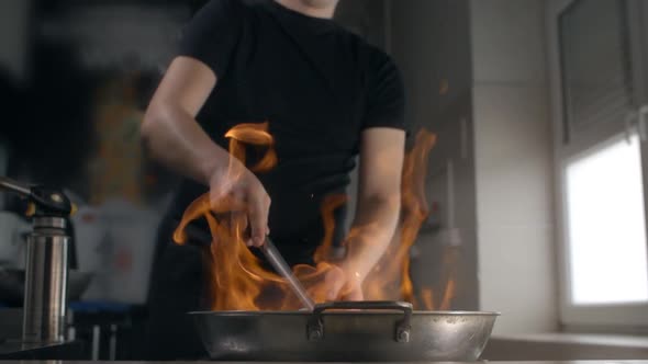 Chef Fries Asian Food in Hot Flaming Wok in Slow Motion, Cooking Chinese Cuisine, Stirring in a Hot