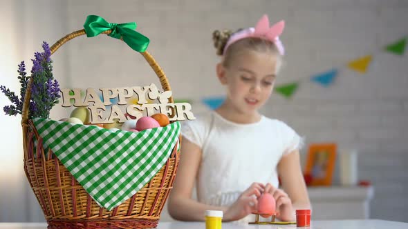 School Girl Painting and Putting Colored Egg in Basket, Holiday Atmosphere