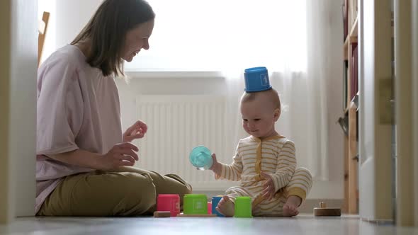 Little Baby Girl and Mommy Play with Colorful Toys at Home Sitting on Floor