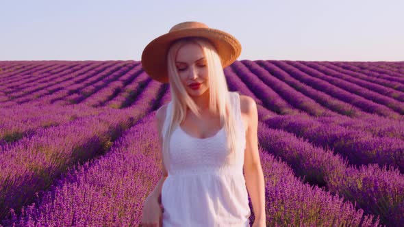 Young Woman in White Dress Walking Through a Lavender Field on Sunset