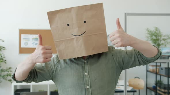 Portrait of Businessman Wearing Breadbag with Smile Emoji Showing Thumbsup Hand Gesture in Workplace