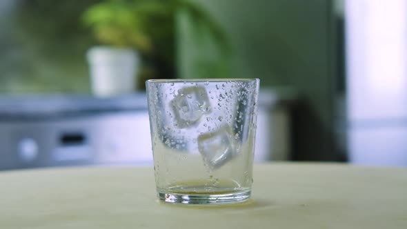 Ice Cubes Fall Into a Glass in the Kitchen in a Home Interior