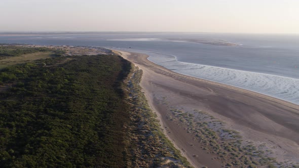 Aerial flight along tidal ocean currents on Oostvoorne bay and lush dune forest