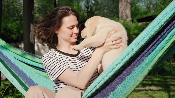 Young Woman Having Fun Playing with Her Little Cute Labrador Puppy