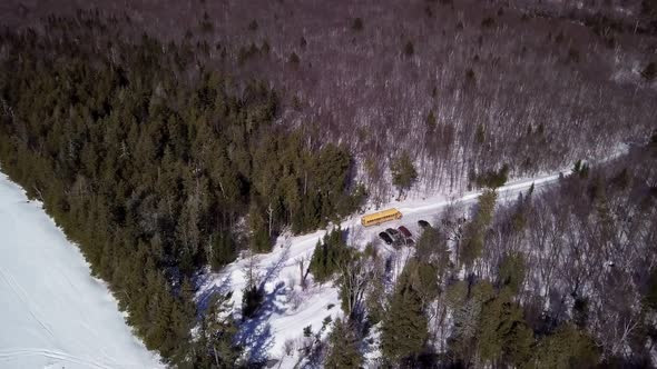 Get an aerial view of a school bus parked next to a frozen Fitzgerald Pond, Maine.