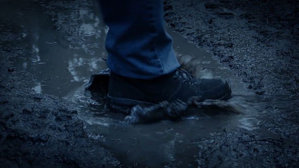 Boot Splashes In Puddle In Forest At Dusk