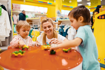ore. Happy mom with daughter and son buying toys in supermarket together, family shopping